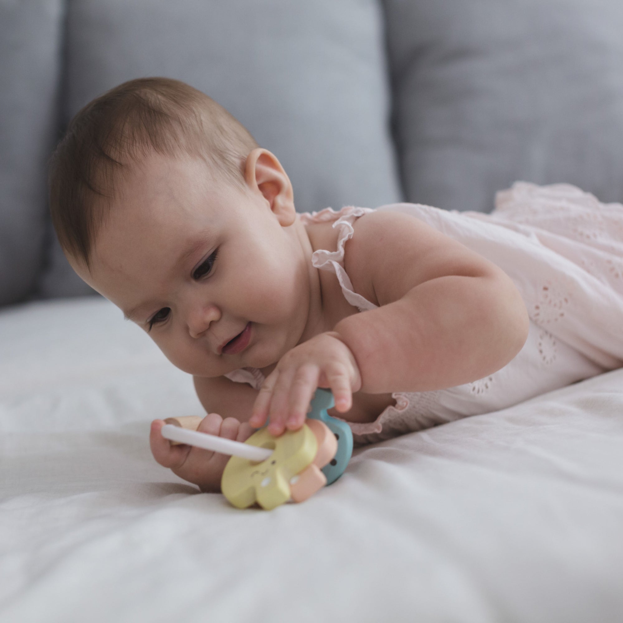 Baby playing with a colorful teething toy on a soft surface