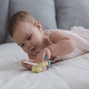 Baby playing with a colorful teething toy on a soft surface